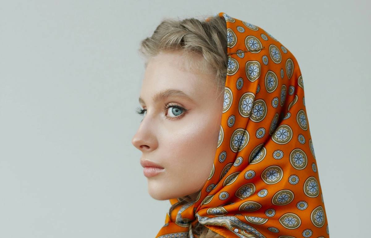 Woman demonstrating how to fold an all-day hair wrap with viscose scarf